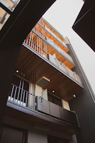 Un edificio de varios pisos con balcones, paneles de madera y un diseño arquitectónico moderno.