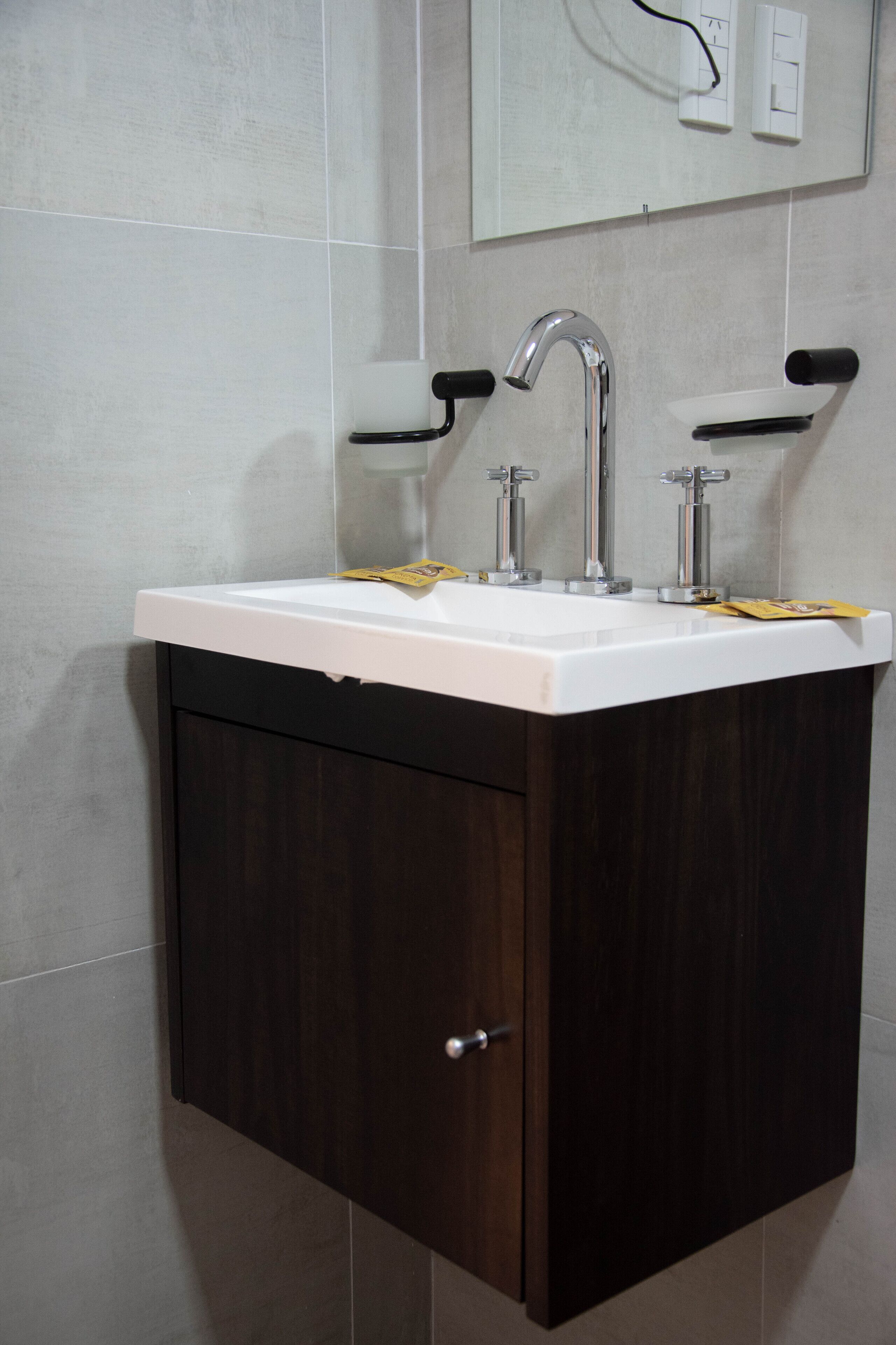 A bathroom with a dark wood vanity, a white sink, and a mirror above the mirror.