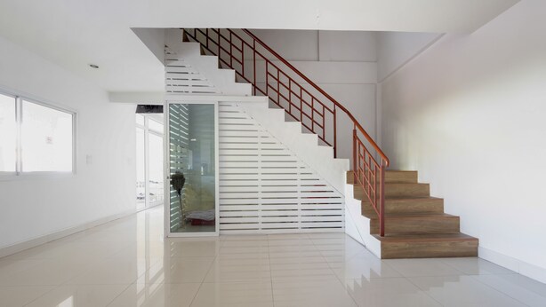Un intérieur moderne avec un escalier, une porte vitrée et un sol carrelé, sobre et élégant.