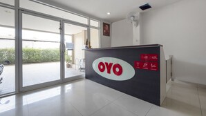 Un espace d’accueil doté d’une porte vitrée donnant sur l’extérieur, un comptoir d’accueil avec un logo et un panneau indiquant les heures d’ouverture.
