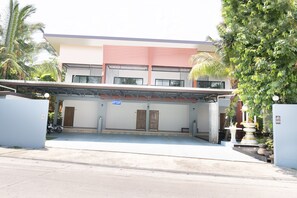 Un bâtiment doté d’un espace de stationnement couvert, d’un panneau indiquant le tarif du stationnement et d’une entrée fermée par un portail.