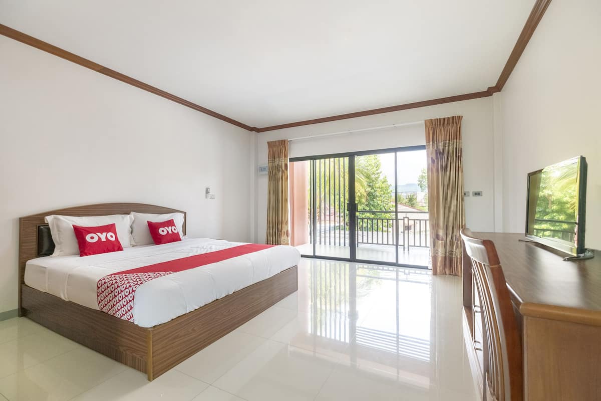 Una habitación de hotel moderna con una cama grande, un balcón con vistas y un escritorio de madera.