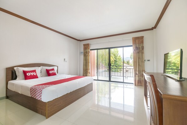 Une chambre d’hôtel moderne avec un grand lit, un balcon offrant une vue agréable et un bureau en bois.