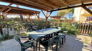 Un patio exterior con una pérgola de madera, una mesa con sillas y vistas a una zona residencial.
