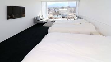 Een hotelkamer met twee bedden, een televisie, een bureau en een groot raam met uitzicht op de stad.