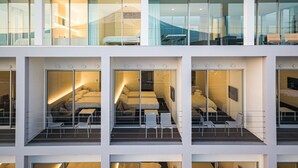 Um hotel moderno com várias varandas, cada uma com assentos e vista para o interior.
