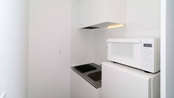Uma cozinha compacta com micro-ondas integrado e fogão por indução de aço inoxidável.