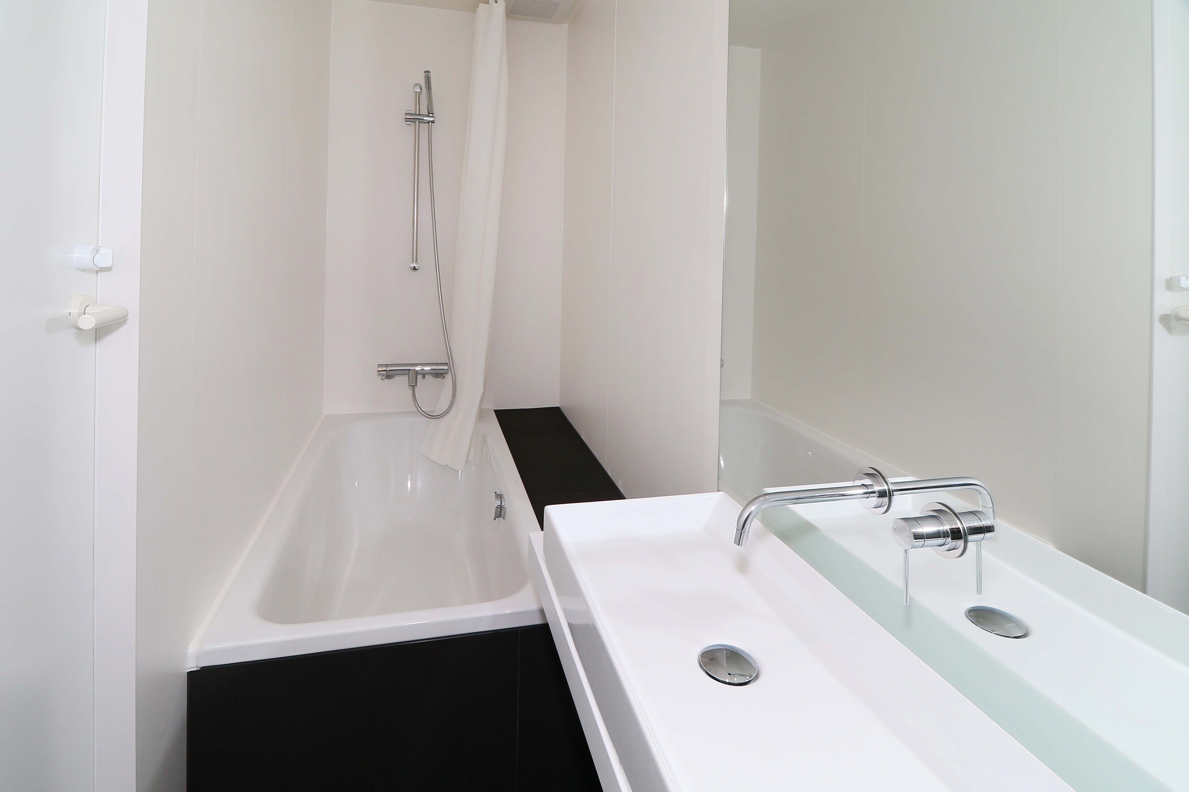 A modern bathroom with a bathtub, a glass-enclosed shower, and a white sink with a chrome faucet.