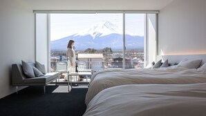 Quarto de hotel com uma grande janela que oferece vista para uma montanha coberta de neve.