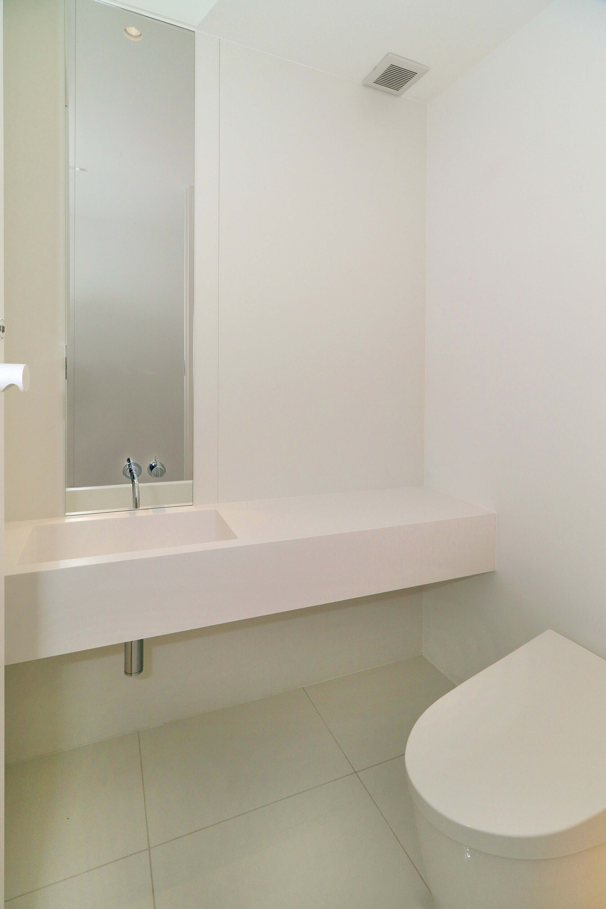 A bathroom with a white sink, a mirror, a toilet, and a shower.