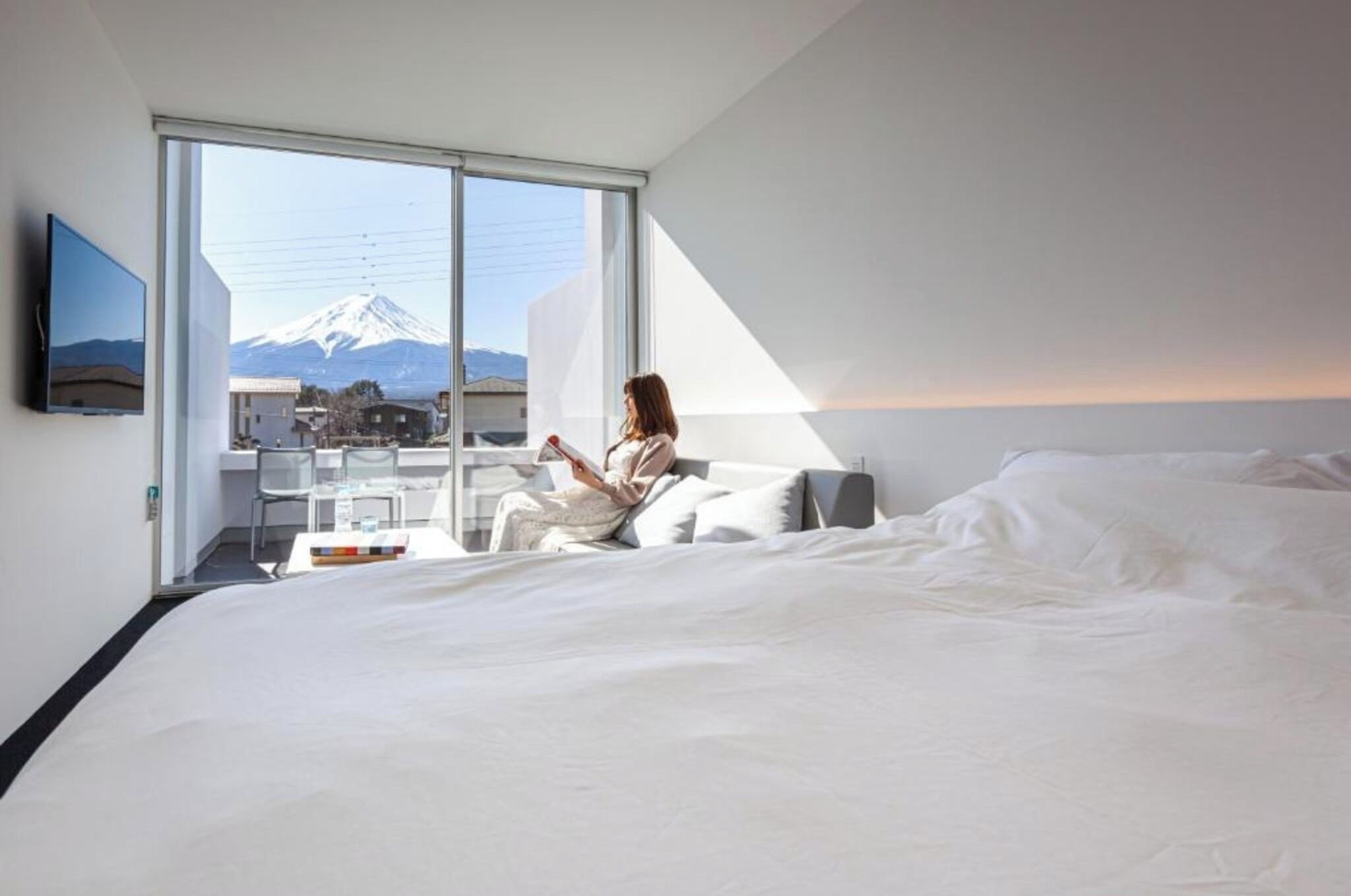 Une chambre d’hôtel avec un lit, un bureau et une grande fenêtre donnant sur une montagne.