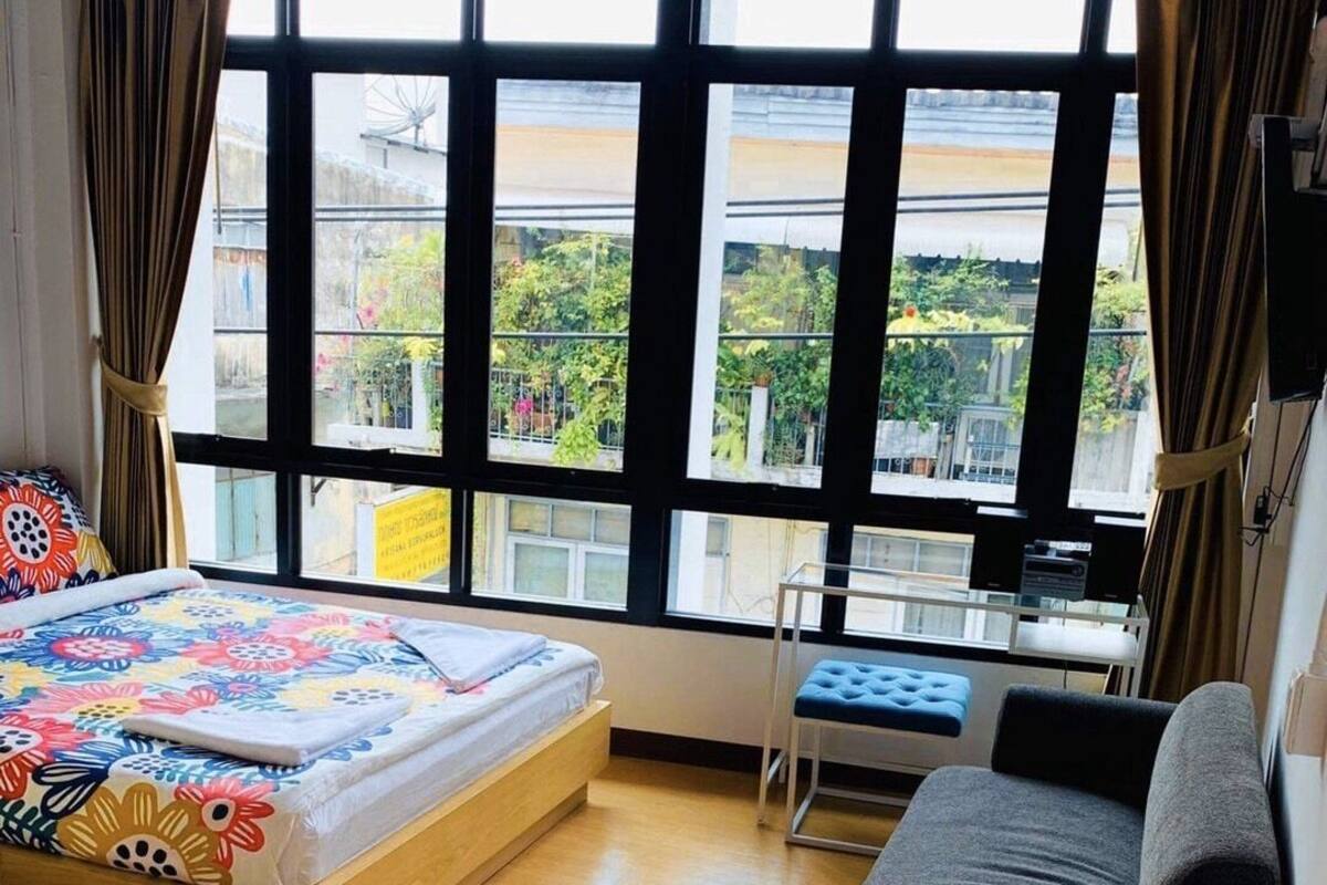 A room with a bed, a sofa, a small table, and a window with curtains.