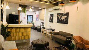 A modern lobby with a reception desk, seating area, and world maps on the walls. - Daraya Hostel (Bangkok)