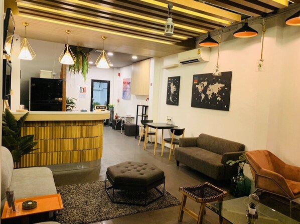 A modern lobby with a reception desk, seating area, and world maps on the walls.