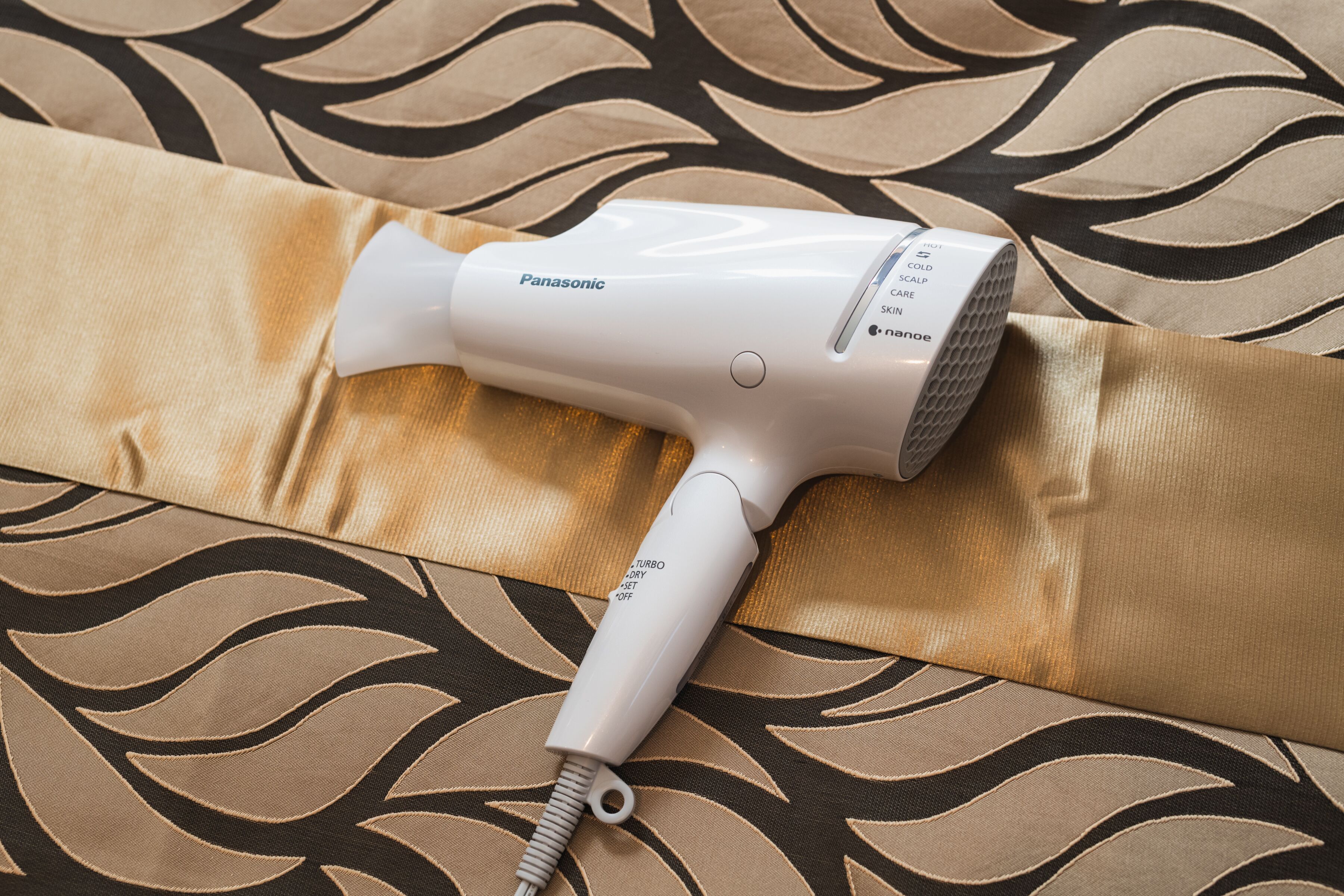 A Panasonic hair dryer on a patterned fabric.