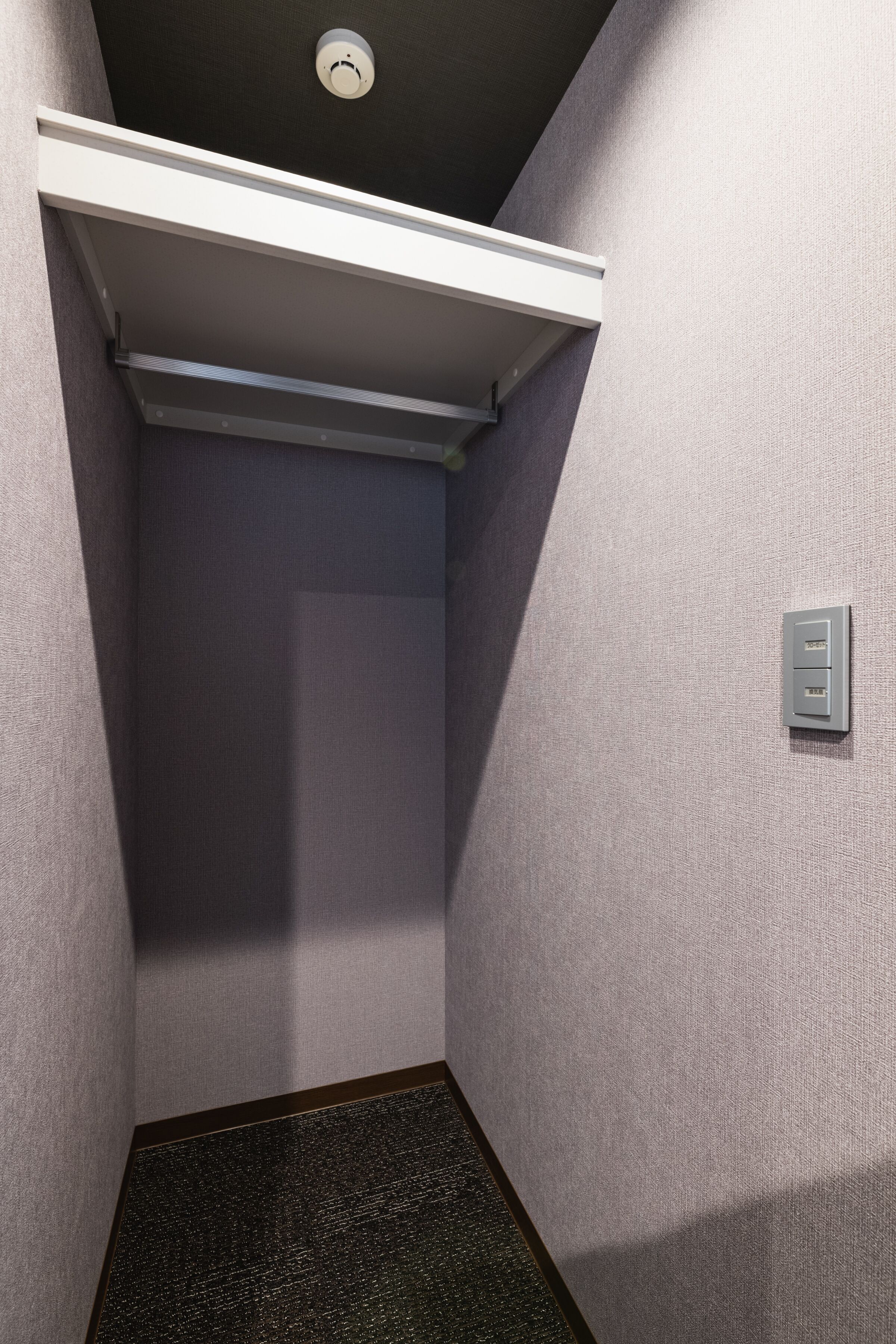 A narrow hallway with a textured wall, a ceiling light, and a door with a handle.