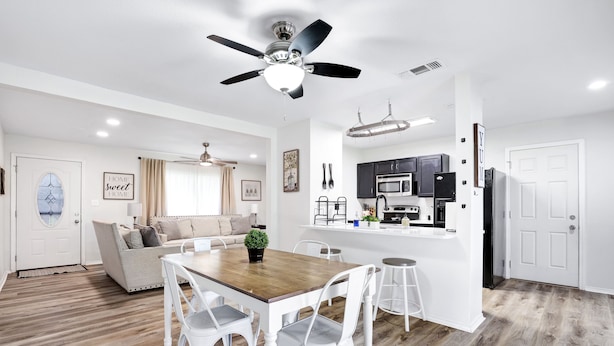 Una cocina moderna con armarios blancos, una isla central y un ventilador de techo.