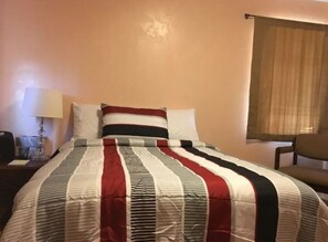 Cozy retreat with a neatly made bed, bedside table, and comfortable chair.