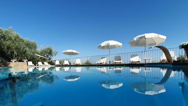 Une piscine aux eaux cristallines, agrémentée de parasols blancs et de chaises longues.