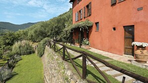 Un bâtiment rouge avec un mur en pierre et une clôture en bois.