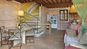 Un intérieur rustique comprenant un coin repas, un escalier, une cuisine et un espace nuit.
