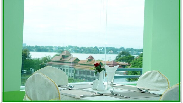 A table set for two with a view of a building across a body of water. - Hotel Bella (Mandalay)