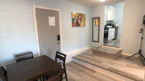 A dining area with a wooden table and chairs, a kitchen in the background, and a mirror on the wall. - Charming Cozy Centralize Studio (San Mateo)