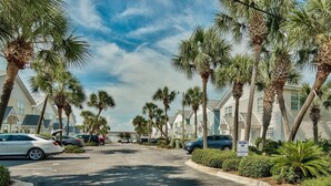 A street lined with palm trees and beach houses, a tow-away zone sign, and parked cars.