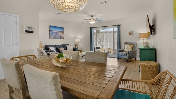 A dining area with a wooden table, chairs, and a hanging light fixture.