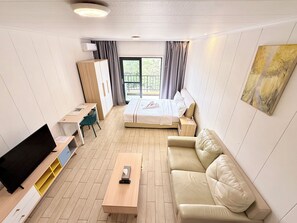 A hotel room with a bed, a sofa, a desk, a TV, and a window with curtains. - Phoenix Apartment by LINK (Kigali)