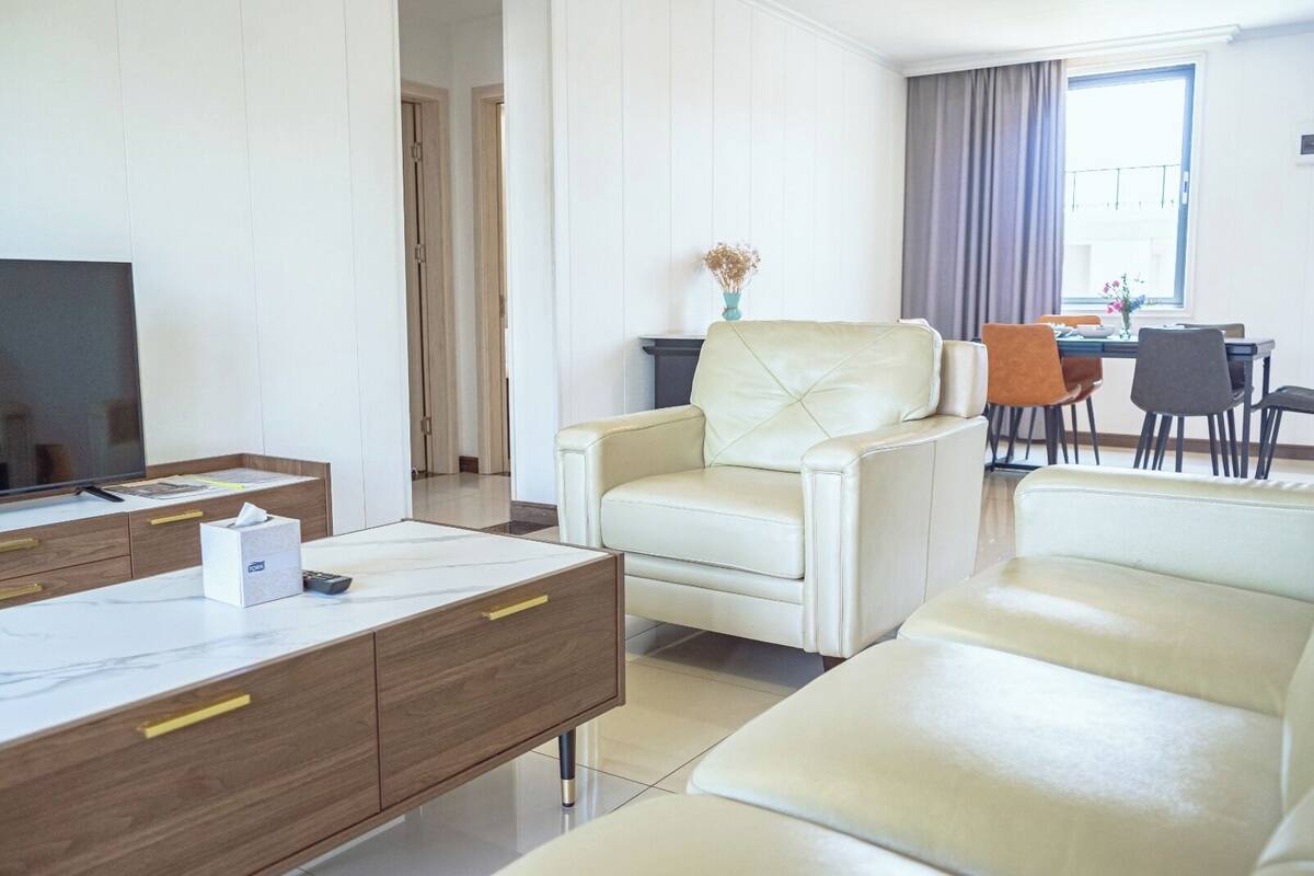 Una sala moderna con un sofá, una mesa de centro y un televisor. Hay un comedor con una mesa y sillas.