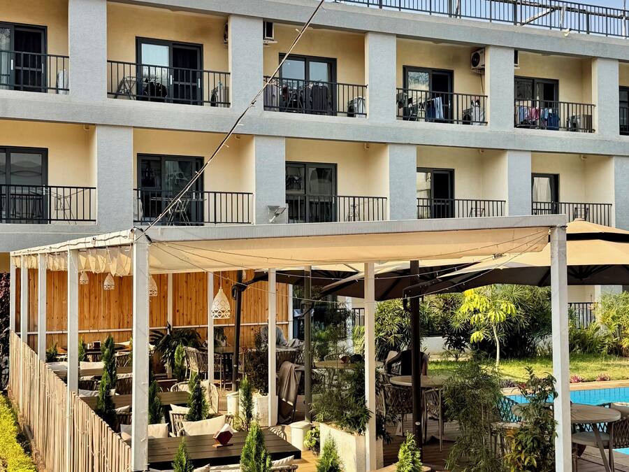 A multi-story hotel with outdoor seating areas, a pool, and a balcony with clothes drying.