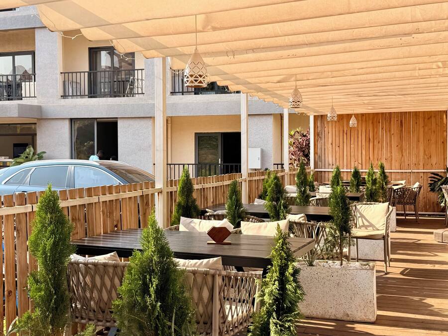 An outdoor patio area with tables and chairs, wooden fences, and potted plants.