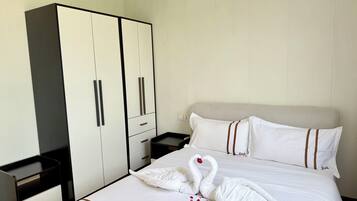 A neatly made bed with a swan towel decoration and the word 'link' on the bedspread.