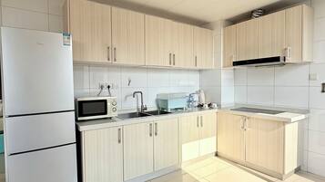 A modern kitchen with a white refrigerator, a microwave, a sink, and wooden cabinets.