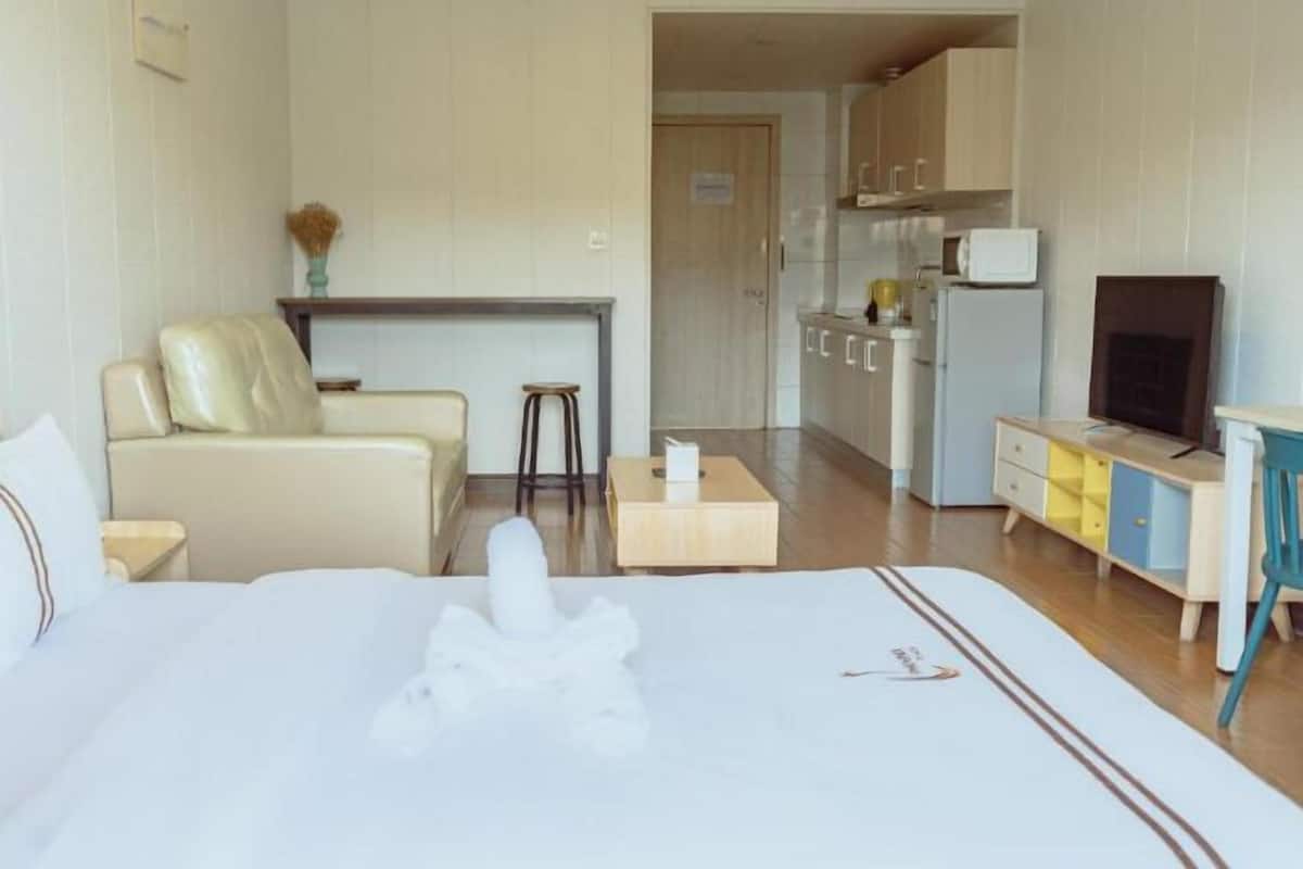 Una habitación de hotel con cama, sofá, kitchenette y televisión.