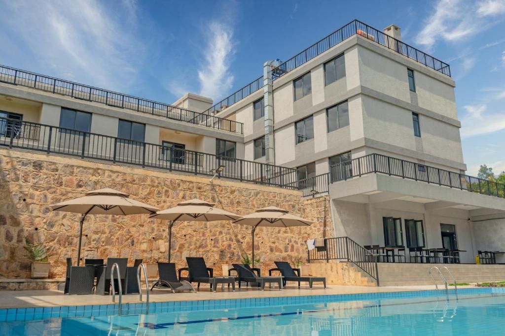 Een meerlaags hotel met een zwembad, terras en een stenen muur.