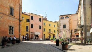 Una piazza con edifici colorati, posti a sedere all'aperto e piante in vaso.