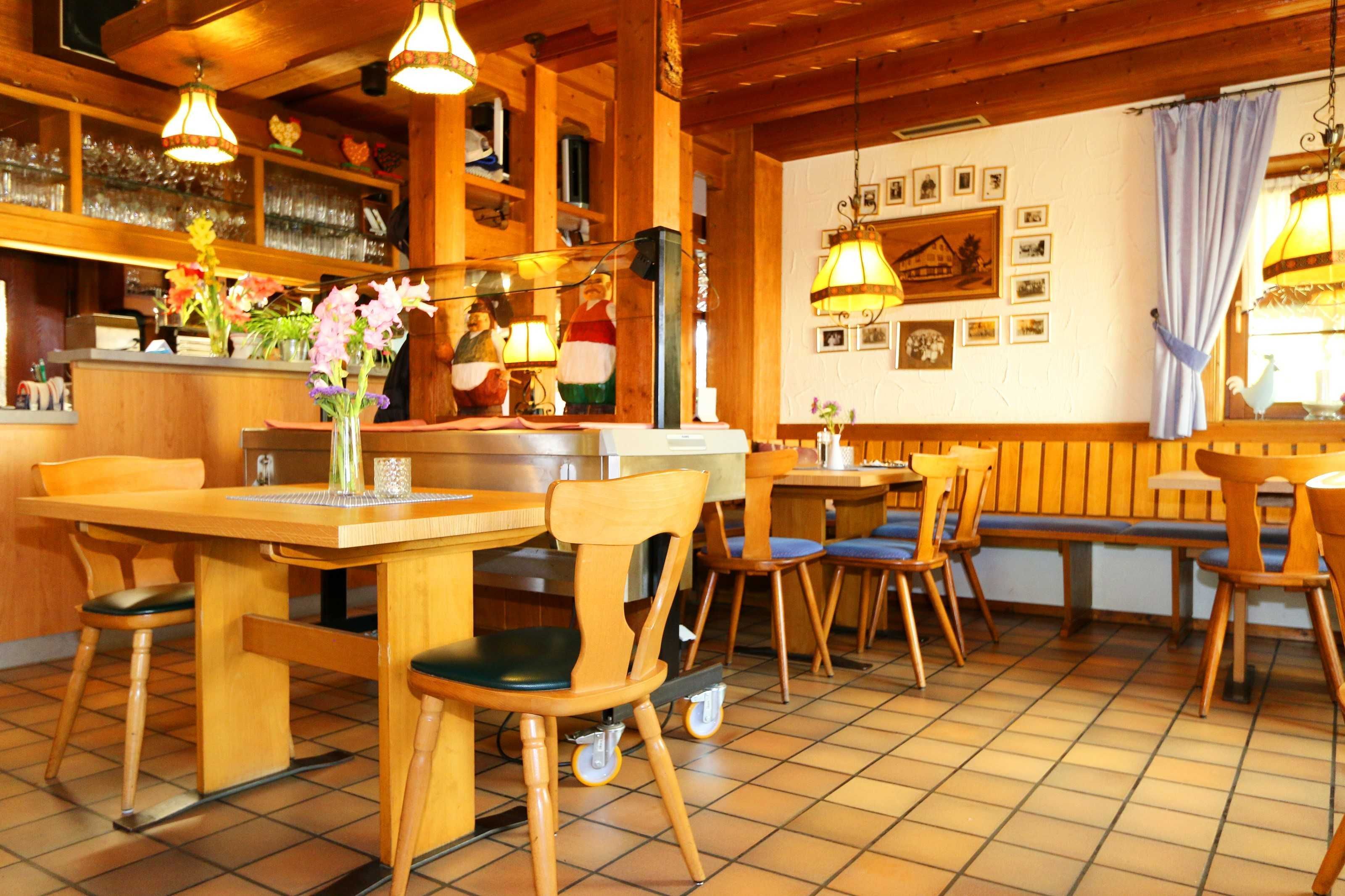 Een restaurantinterieur met houten meubels, een bar en een betegelde vloer.