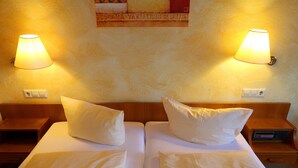 Una cama doble con dos almohadas, una mesita de noche con una lámpara y un cuadro en la pared.