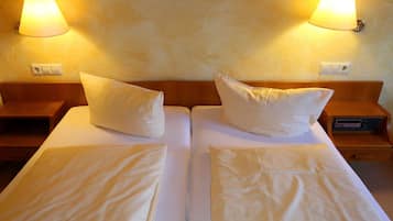 Ein Doppelbett mit zwei Kissen, ein Nachttisch mit Lampe und ein Bild an der Wand.