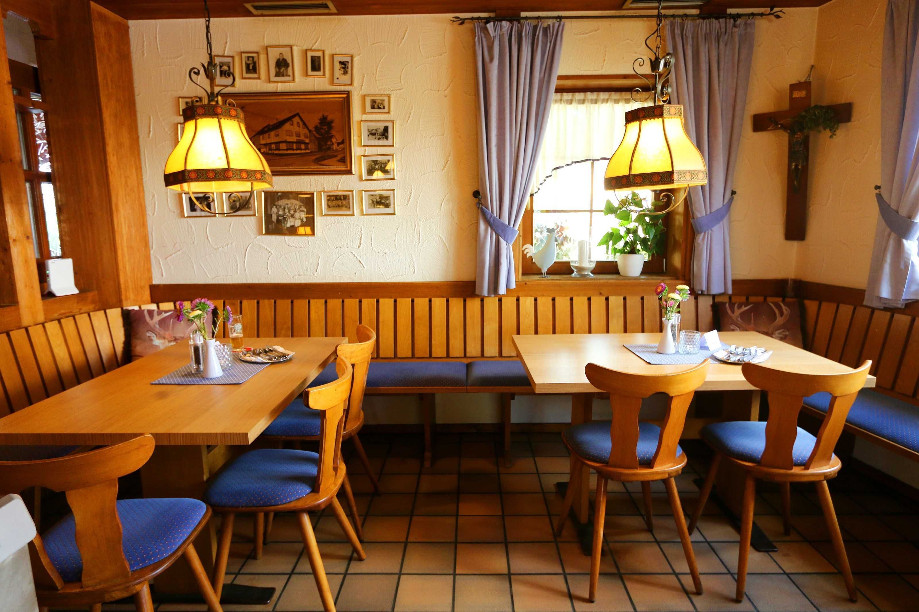Ein Restaurant mit Holztischen, blauen Sitzkissen und einem Kreuz an der Wand.