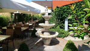 Un patio con una fuente de piedra, asientos exteriores y sombrillas.
