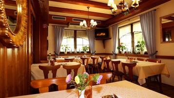 A restaurant with wooden interiors, multiple tables, and chairs.