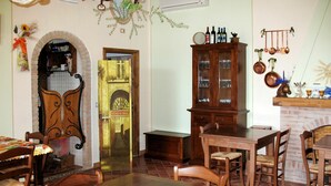 A dining area with a brick fireplace, wooden furniture, and a cabinet with glass doors. - Nice apartment in villa for 2 people with pool, WIFI, TV and patio (Lajatico)