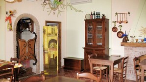A dining area with a wooden table and chairs, a cabinet with glass doors, and a brick fireplace. - Beautiful apartment in villa for 4 people with WIFI, pool, TV and patio (Lajatico)