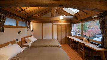 A cozy room with two beds, a desk, and a window with a view of autumn trees.