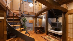 Una scala in legno conduce a una zona mansardata con camino e scrivania.