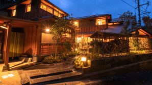Una casa tradizionale giapponese con facciata in legno, tetto in tegole e una scala in legno che conduce all'ingresso.