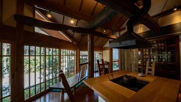 A spacious room with large windows, wooden beams, and a central table with a sink.